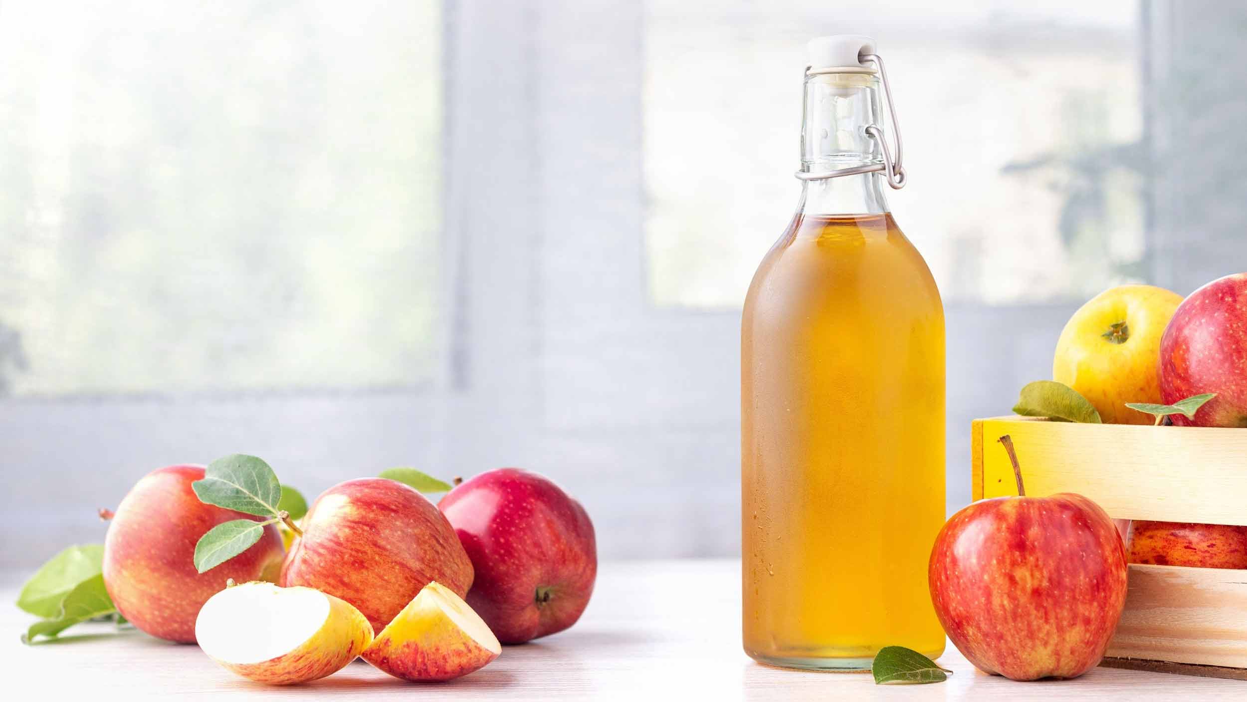 Apple cider vinegar bottle with fresh apples – natural health remedy.